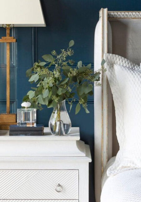 elegant white bed with side table, lamp and vase